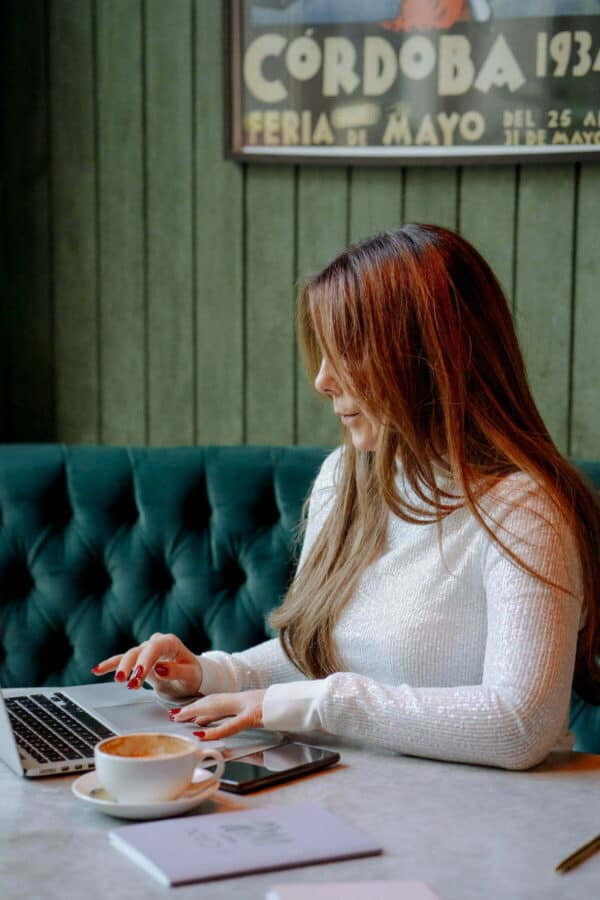 Anne-Marie Mayers working on her laptop in a clam creative workspace, symbolising growth and professional development through the ELEVATE holistic coaching course bundle.